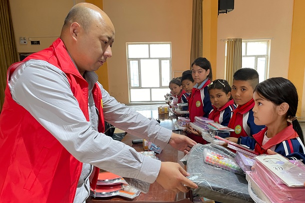 圖為張成國給學(xué)生贈送文具