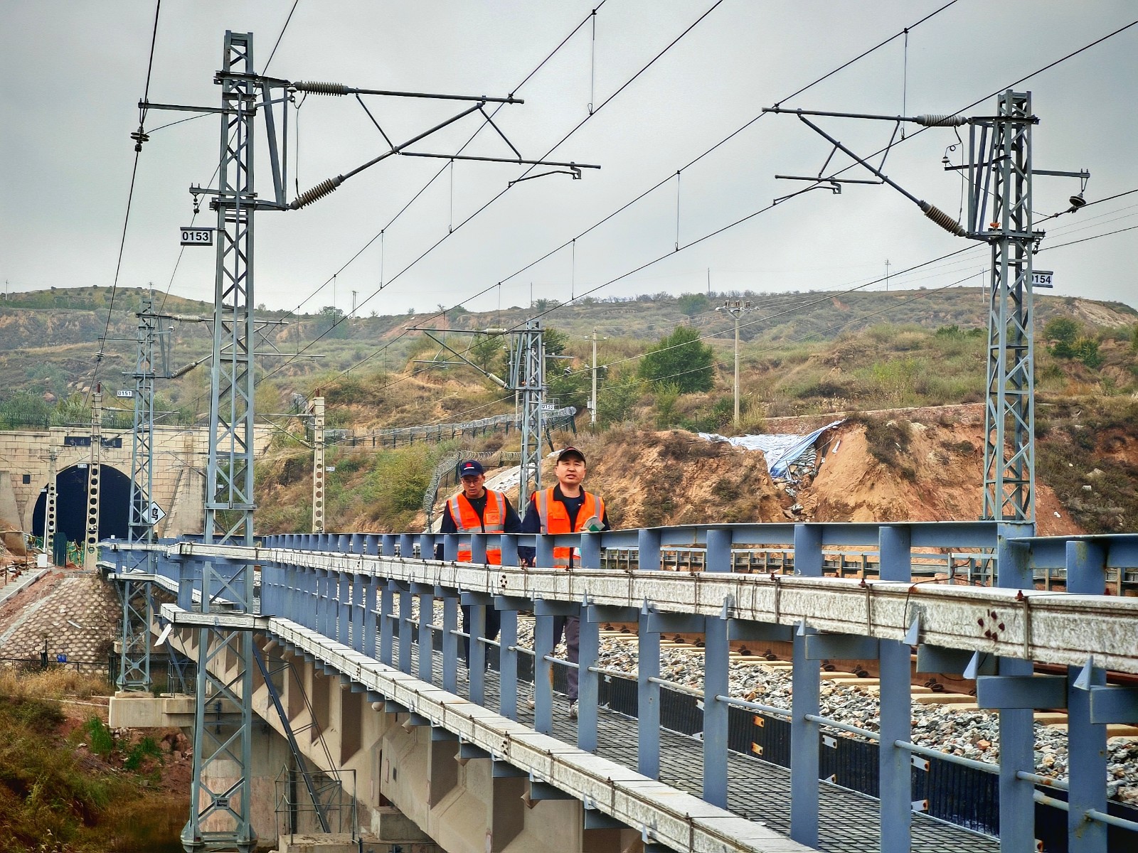 圖為應(yīng)急小組人員徒步通過隧道后在鐵路橋上排查應(yīng)急線路